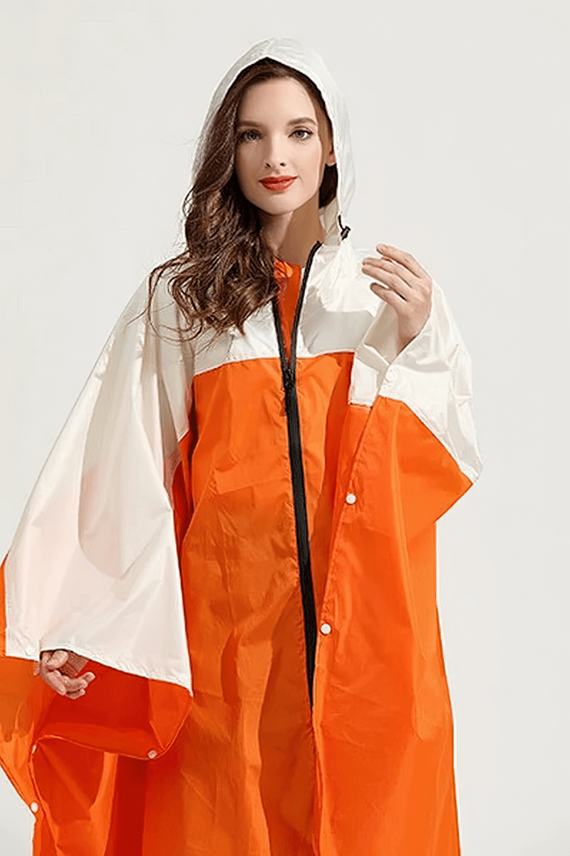 Woman modeling orange and white raincoat poncho with hood, zipper; waterproof and windproof design for rainy days.